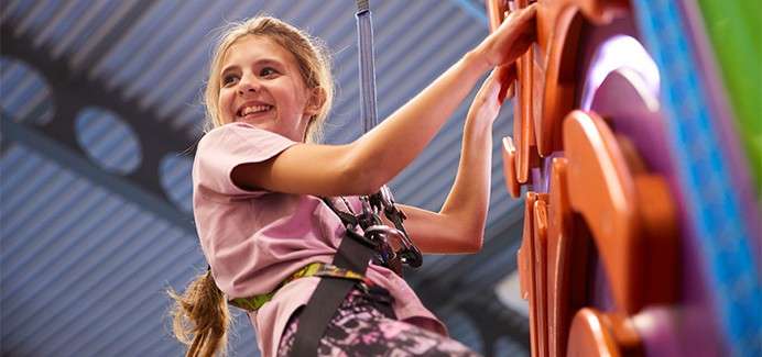 A girl climing on the indoor climbing wall.