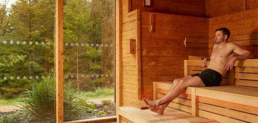 A man in the sauna looking out to the forest.