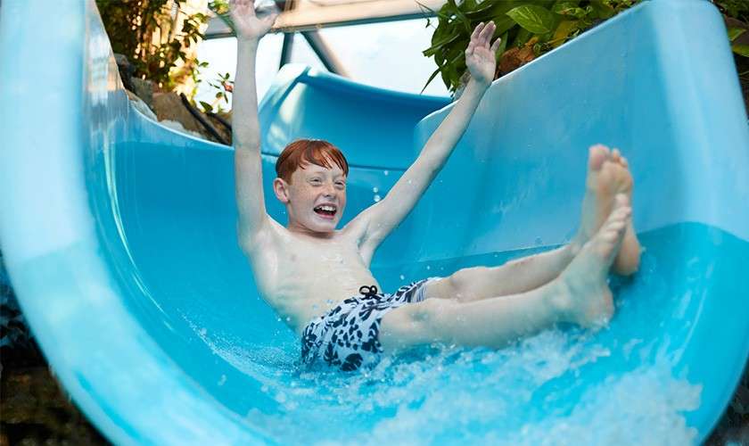 A school aged boy going down a slide in the Subtropical Swimming Paradise.