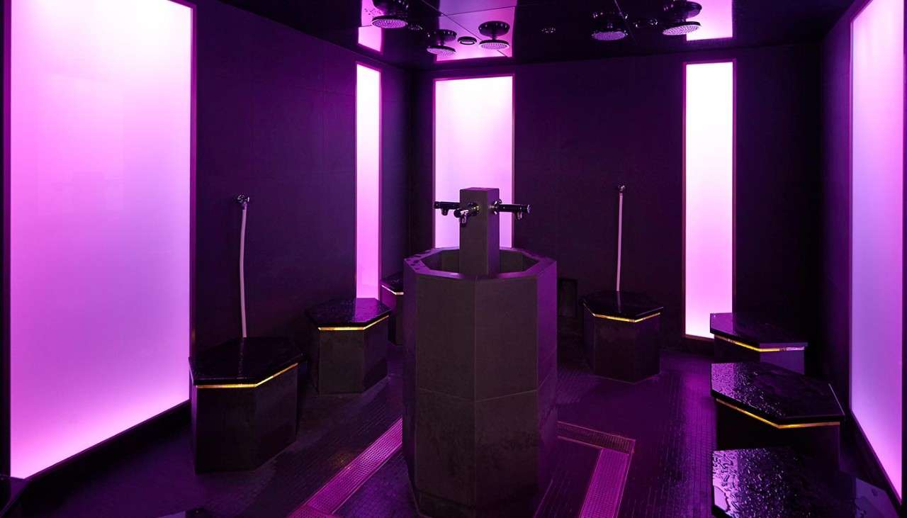 Mineral steam room with tall pillars bathed in purple light.