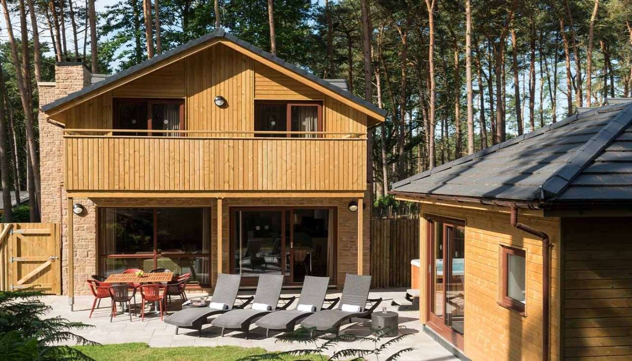 An external shot of an Adapted Exclusive Lodge showing sun loungers and the outdoor seating area. 