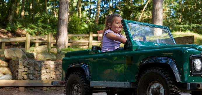 A little girl driving a mini truck in the off road explorers.