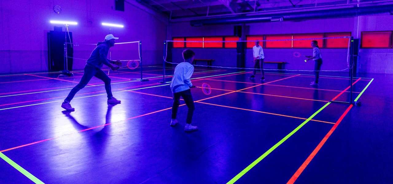 Family playing badminton in a UV lit room
