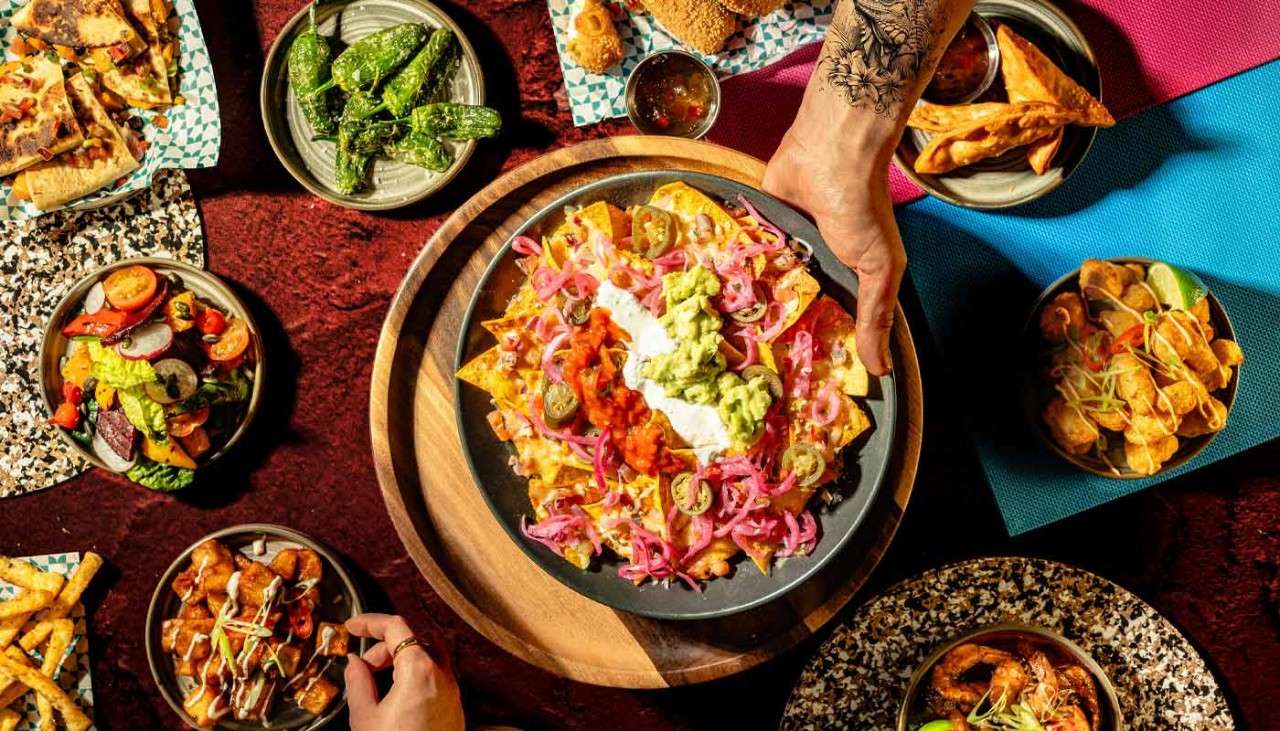 Large bowl of Nachos surrounded by Tapas dishes