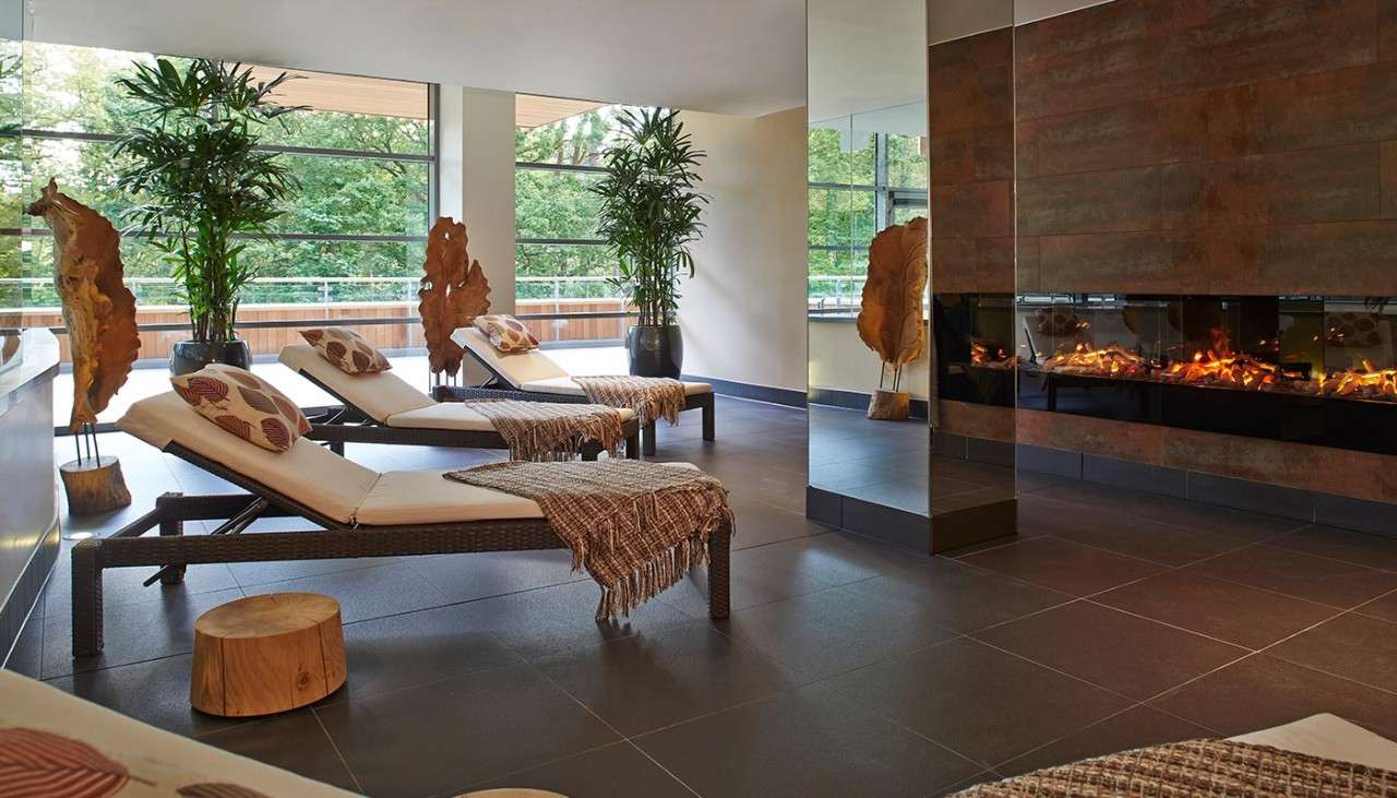 Lounge chairs inside an open space with a roaring fire.